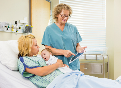 picture of woman in hospital bed with baby and nurse