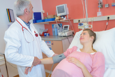 pregnant patient in bed being examined by doctor