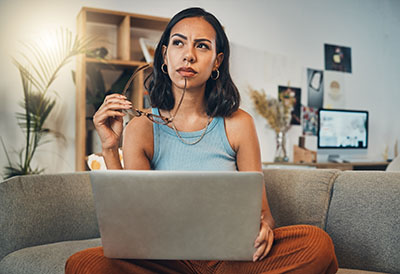 photo of woman sitting on the couch with a laptop