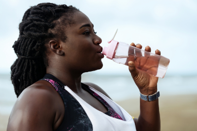 woman drinking water after exercising